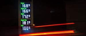 Autos fahren an einer Tankstelle vorbei, an der die Kraftstoffpreise angezeigt sind.