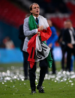 Italiens Trainer Roberto Mancini geht über den Platz, eingehüllt in eine Italienflagge. Foto: Laurence Griffiths/Pool Getty Images/AP/dpa