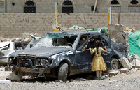 Eine Frau und ein Kind betrachten ein Auto, das bei den Luftangriffen der Militärallianz auf Sanaa zerstört worden ist. Foto: AFP