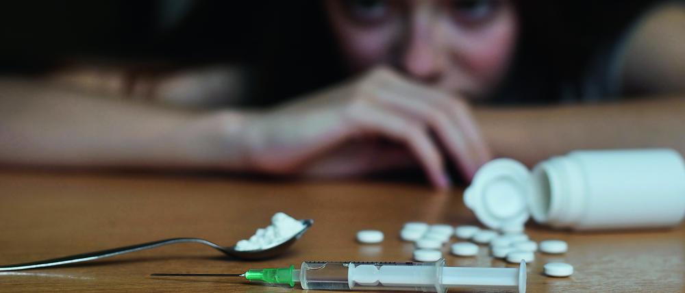 Eine Drogenabhängige schaut auf eine Heroinspritze. 