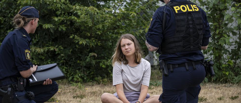 Zwei Polizeibeamte sprechen mit der Klimaaktivistin Greta Thunberg (Archivbild). 