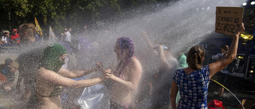 Klimaaktivisten tanzen im Wasserstrahl eines Wasserwerfers der niederländischen Polizei während einer Klimaprotestaktion von Extinction Rebellion.