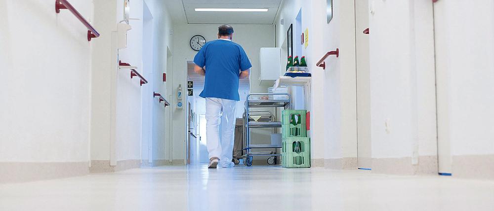 Ein Krankenpfleger geht über einen Flur in einem Krankenhaus. 
