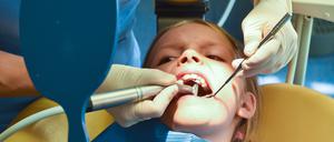 Ein siebenjähriges Mädchen wird von einer Zahnärztin behandelt. 