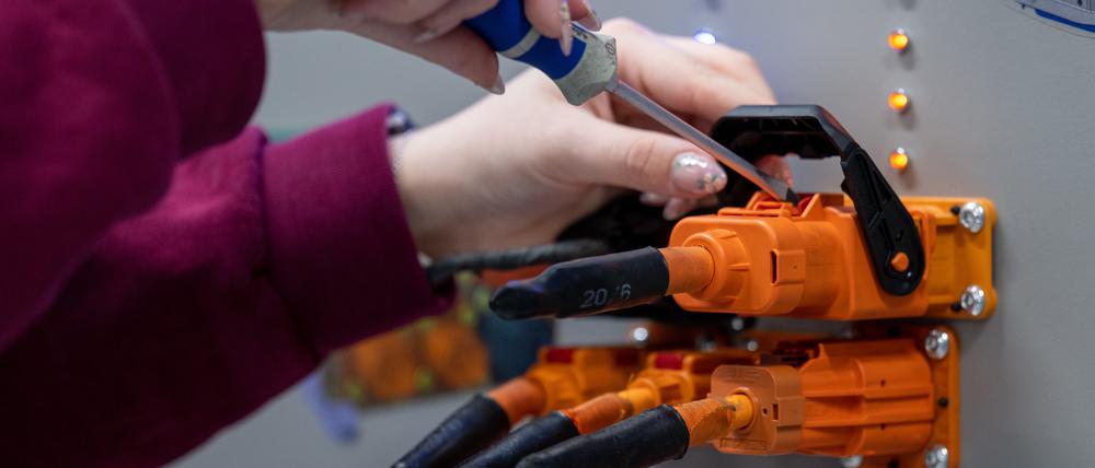  Eine angehenden KfZ-Mechatronikerin überprüft im Volkswagen Bildungsinstitut in Zwickau Stecker für ein Ladegerät.