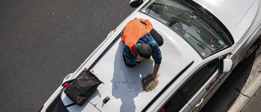Ein Aktivist der Gruppe Letzte Generation hat sich bei einer Blockade auf der Autobahn 100 auf einem Autodach festgeklebt.  