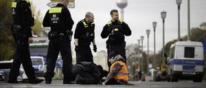 Polizisten lösen eine Aktivistin der Gruppe „Letzte Generation“ von der Kreuzung Frankfurter Tor, die sich bei einer Sitzblockade mit einer Hand am Asphalt festgeklebt hat. 