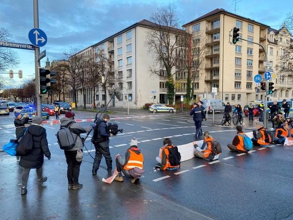 Demonstranten blockieren eine Straße in München. 