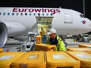 Ein Airbus A320-214 der Fluggesellschaft Eurowings mit Ziel Stuttgart wird auf dem Flughafen Berlin Brandenburg (BER) mit Plastikboxen voller Briefe und anderer Post beladen.