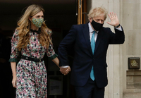 Premier Johnson winkt, als er mit Verlobter Carrie Symonds nach ihrer Stimmenabgabe das Londoner Methodist Central Hall verlässt. Foto: Matt Dunham/dpa