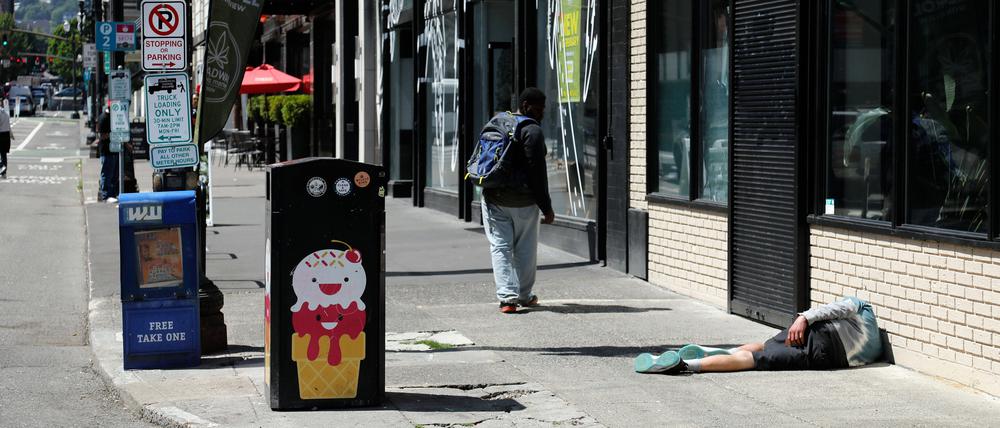 Ein Mann liegt auf dem Fußweg in Downtown Portland. In den USA ziehen Opioide Menschen seit Jahren in den Abgrund. Den Schmerzmitteln wird oft „Tranq“ oft beigemischt.