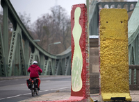 Originalteile der ehemaligen Berliner Mauer stehen in Potsdam (Brandenburg) vor der Kulisse der historischen Glienicker Brücke. Foto: Ralf Hirschberger/dpa