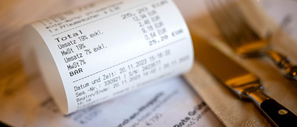 Eine Rechnung mit Umsatzsteuer und Mehrwertsteuer liegt auf der Speisekarte eines Restaurants.