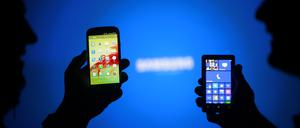 Men are silhouetted against a video screen as they pose with Samsung Galaxy S3 and Nokia Lumia 820 smartphones in this photo illustration taken in the central Bosnian town of Zenica, May 17, 2013. REUTERS/Dado Ruvic (BOSNIA AND HERZEGOVINA - Tags: BUSINESS TELECOMS)