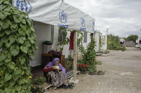 Eine Frau trinkt Tee vor ihrer Unterkunft im Flüchtlingslager Schisto bei Athen. Foto: Socrates Baltagiannis/dpa