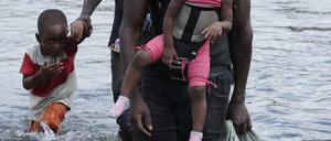 Panama, Panama-Stadt: Migranten aus Haiti überqueren am 10. Februar 2021 den Fluss Tuquesa nach einer Reise zu Fuß durch den Dschungel nach Bajo Chiquito, in der Provinz Darien.