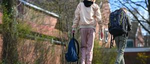 Eine Schülerin geht in einer Jogginghose auf dem Schulhof einer Schule.
