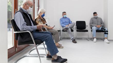 Menschen warten mit Mundschutz in einer Arztpraxis. Die Kassenärztlichen Vereinigung Berlin bemängelt eine krisenhafte Versorgungssituation in den ambulanten Praxen. 