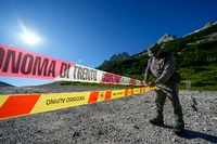 Ein Beamter der italienischen Finanzpolizei blockiert den Zugang zum Marmolada-Berg und zum Punta-Rocca-Gletscher in den italienischen Alpen mit Absperrband. Foto: Luca Bruno/AP/dpa