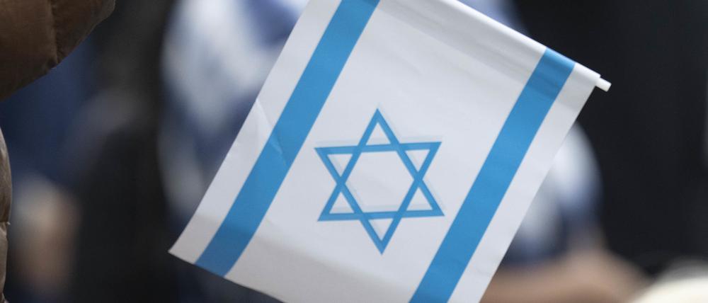 Ein Teilnehmer einer Kundgebung hält eine Kerze und eine Israelflagge in der Hand. (Symbolbild)