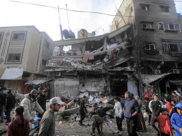 Palästinenser gehen vor stark beschädigten Gebäuden nach einem israelischen Angriff in Chan Junis. 