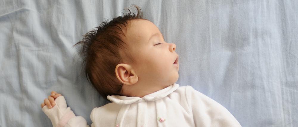 Newborn baby girl sleeping on blue sheets at home