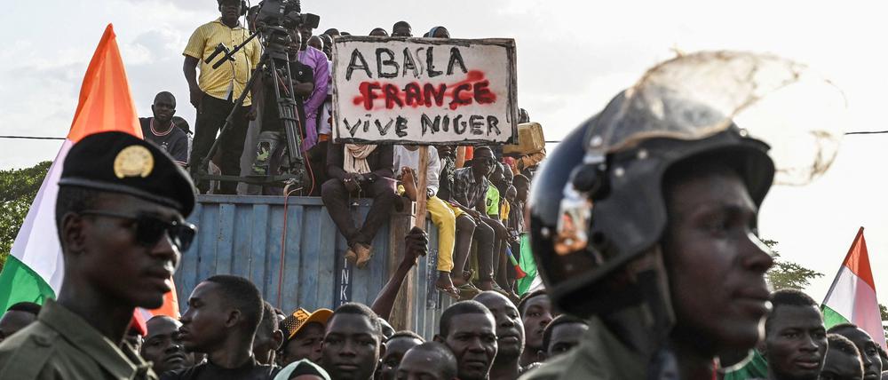 Anhänger des Nationalen Rates für den Schutz des Vaterlandes (CNSP) von Niger halten ein Plakat, während Menschen vor dem nigrischen und französischen Luftwaffenstützpunkt protestieren, um den Abzug der französischen Armee aus Niger zu fordern, in Niamey am 16. September 2023. 