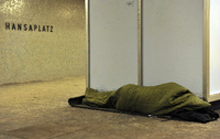 Ein Obdachloser liegt unter einer Decke in einem Eingang einer Kirche in Kreuzberg. Paul Zinken/dpa