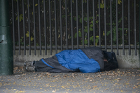 Ein Obdachloser liegt in einem Schlafsack gehüllt unter einem Dachvorsprung vor dem Berliner Zoo. dpa