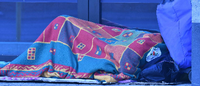 Ein Obdachloser schläft in Decken gehüllt in einem Hauseingang im Tiergarten. Foto: Paul Zinken/dpa