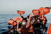 Ein Helfer versorgt Migranten mit Rettungswesten. Foto: dpa/Flavio Gasperini/SOS Mediterranee