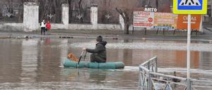 Nachdem ein Damm in der russischen Stadt Orsk gebrochen ist, paddelt ein Mann mit seinem Hund auf einem Schlauchboot durch die überfluteten Straßen.