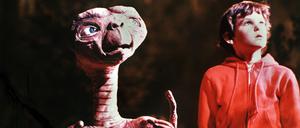 Henry Thomas als „Elliot“ und der Außerirdische „E.T.“ in einer Szene des gleichnamigen Fantasy-Films von Steven Spielberg. Das kleine Schrumpelwesen von einem fernen Planeten wird aus Versehen von seiner Raumschiff-Besatzung auf der Erde zurückgelassen, freundet sich mit einer Kindergruppe an und stiftet heillose Verwirrung. Sein größter Wunsch, „nach Hause“ zurückzukehren, geht nach einem Telefonat mit seinem Heimatplaneten in Erfüllung. „E.T.“ lief am 9. Dezember 1982 in den deutschen Kinos an und war so erfolgreich, dass er über zehn Jahre Platz eins der Liste der erfolgreichsten Filme anführte.