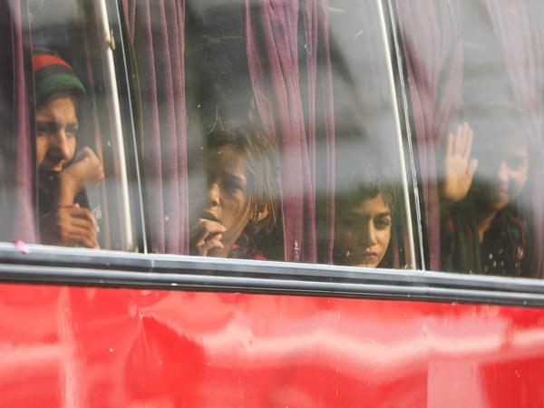 Afghanische Kinder schauen aus den Fenstern eines Busses, der sie von Pakistan nach Afghanistan bringt. 