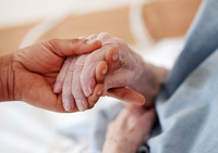 Eine Pflegerin hält einem Altenheim die Hand einer Bewohnerin. (Symbolbild) Foto: Oliver Berg/dpa