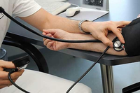 Ein Arzt misst den Blutdruck einer Patientin.