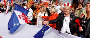 Demonstranten schwenken die EU-Flagge und die polnische Flagge, als sie sich am 1. Oktober 2023 im Zentrum Warschaus zu dem von der Opposition organisierten „Marsch der Millionen Herzen“ versammeln.