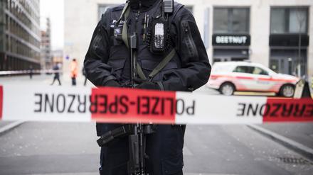 Ein schwer bewaffneter Polizist steht hinter einem Absperrband in der Züricher Innenstadt. 