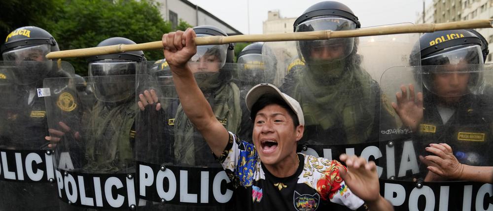 Ein regierungskritischer Demonstrant protestiert in Lima vor einer Reihe von Polizisten. 