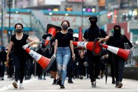 Demonstranten auf dem Weg, um Straßensperren zu bauen. Die Verkehrshütchen werden auch über rauchende Tränengaskanister gestülpt. Foto: Thomas Peter/Reuters