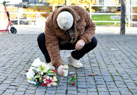 Ein Mann legt Blumen nieder, am Tatort an dem der schwedische Rapper Einar erschossen wurde. Foto: dpa/Henrik Montgomery/TT NEWS AGENCY