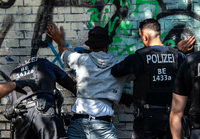 September 2019: Berliner Polizeibeamte kontrollieren in einem Park einen Mann mit dunkler Hautfarbe als mutmaßlichen Drogendealer. Foto: Paul Zinken/dpa