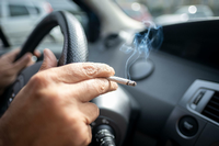 Ein Mann sitzt rauchend am Lenkrad eines Autos. Foto: Peter Steffen/dpa