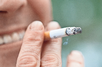 Eine Frau steht auf einer Straße und hält eine Zigarette in der Hand. Foto: Finn Winkler/dpa