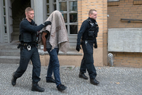 Polizisten führen einen verdächtigen Mann nach einer Razzia im Ortsteil Tiergarten ab. (Archivbild vom August 2018) Foto: Paul Zinken/dpa