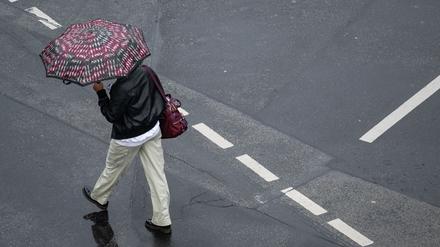 Mit einem Schirm schützt sich eine Passantin in Frankfurt vor dem strömenden Regen. 