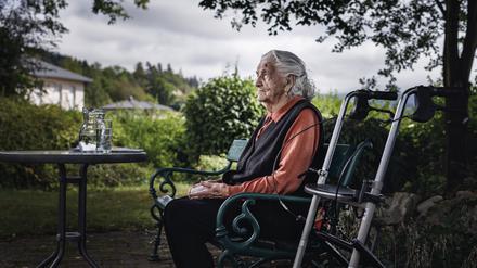 Eine alte Dame auf einer Parkbank.