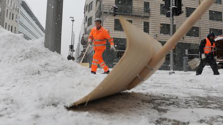 Mitarbeiter der Stadtreinigung räumen in Berlin-Mitte den Schnee an einer Straßenkreuzung. 