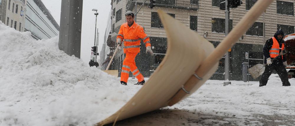 Mitarbeiter der Stadtreinigung räumen in Berlin-Mitte den Schnee an einer Straßenkreuzung. 