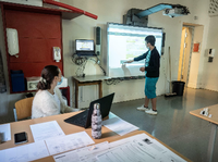 Ein Schüler steht an einem großen Bildschirm vor der Klasse und bearbeitet einen Text, seine Lehrerin sitzt an einem Laptop. Foto: Frank Rumpenhorst/dpa